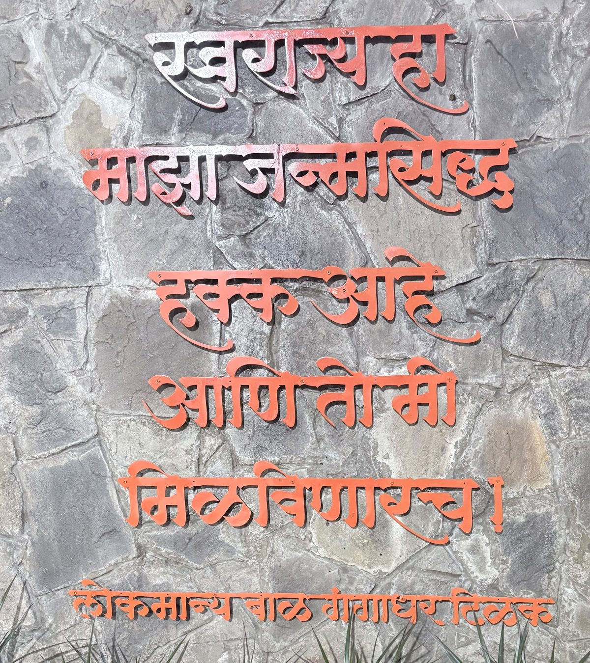 दगडी भिंतीवर धातूच्या अक्षरांत: स्वराज्य हा माझा जन्मसिद्ध हक्क आहे आणि तो मी मिळविणारच! — लोकमान्य बाळ गंगाधर टिळक